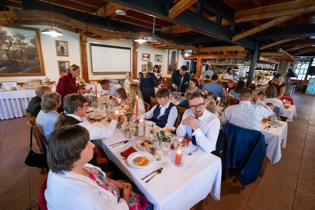 Svatební hostina s hosty a obsluhou v dřevěném interiéru Na Kamínce
