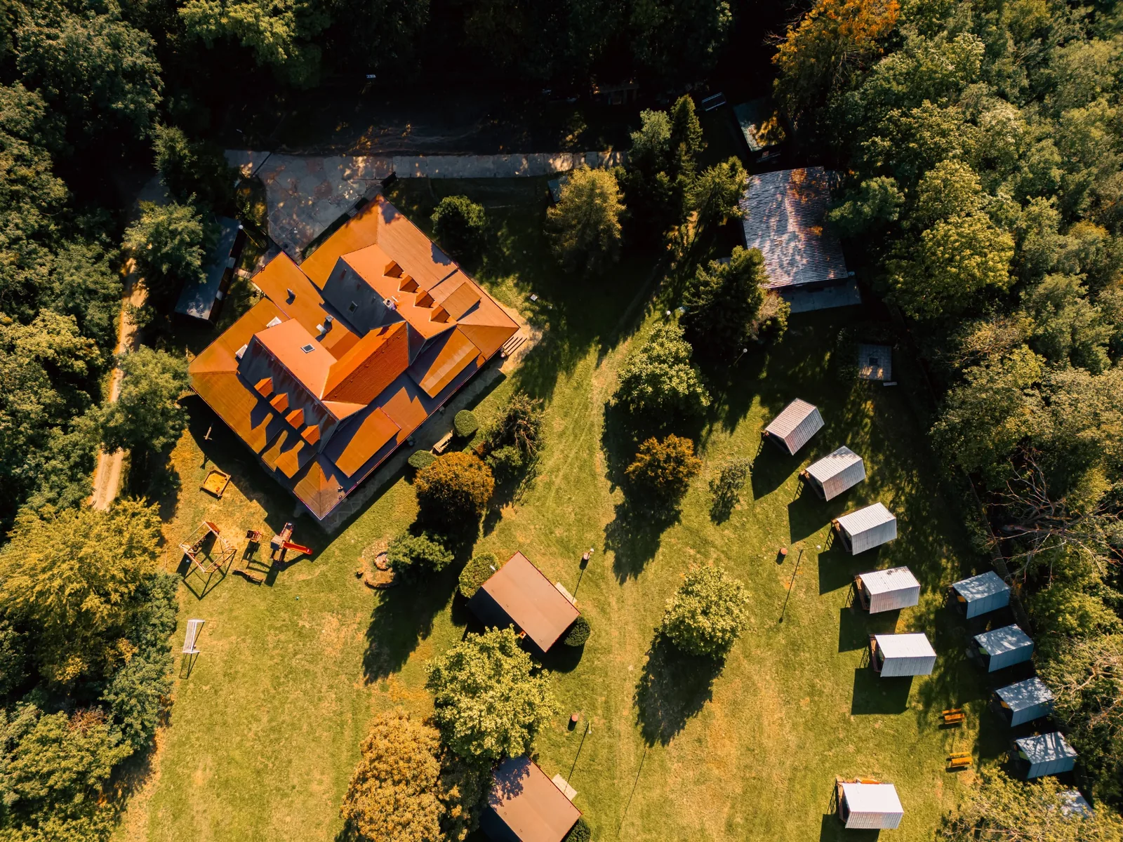 Letecký pohled na hlavní budovu a areál Na Kamínce obklopený lesy